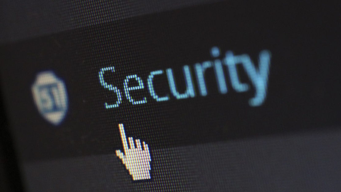 Close up on a pc monitor with the word "Security" spelled in big letters as a mouse hand cursor is ready to click it.