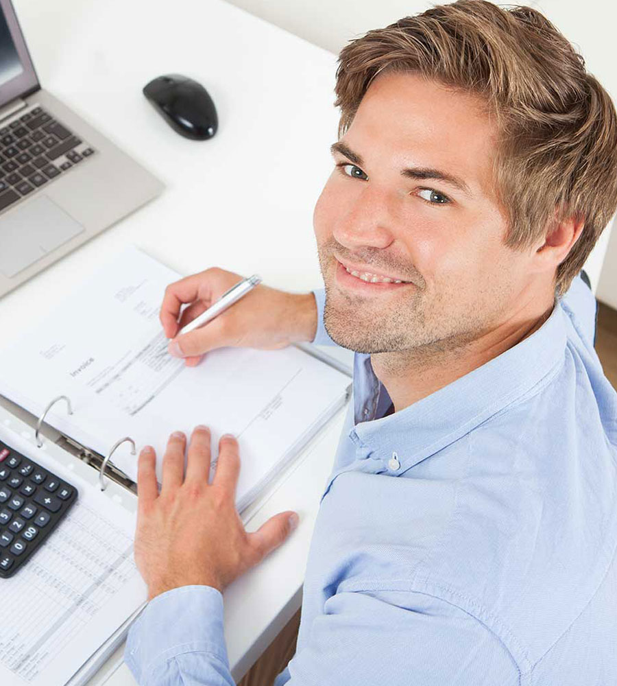 a person sitting at a desk writing on a binder