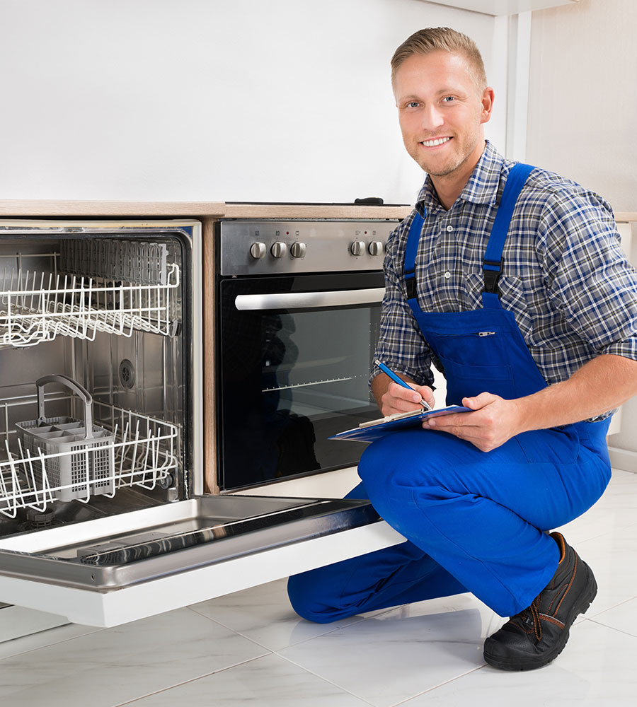 a person in blue overalls kneeling next to an open dishwasher