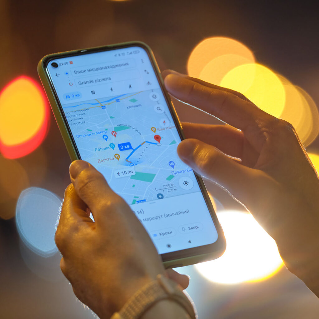 Close up of female hands holding cellphone with Google maps navigation app searchig for direction .