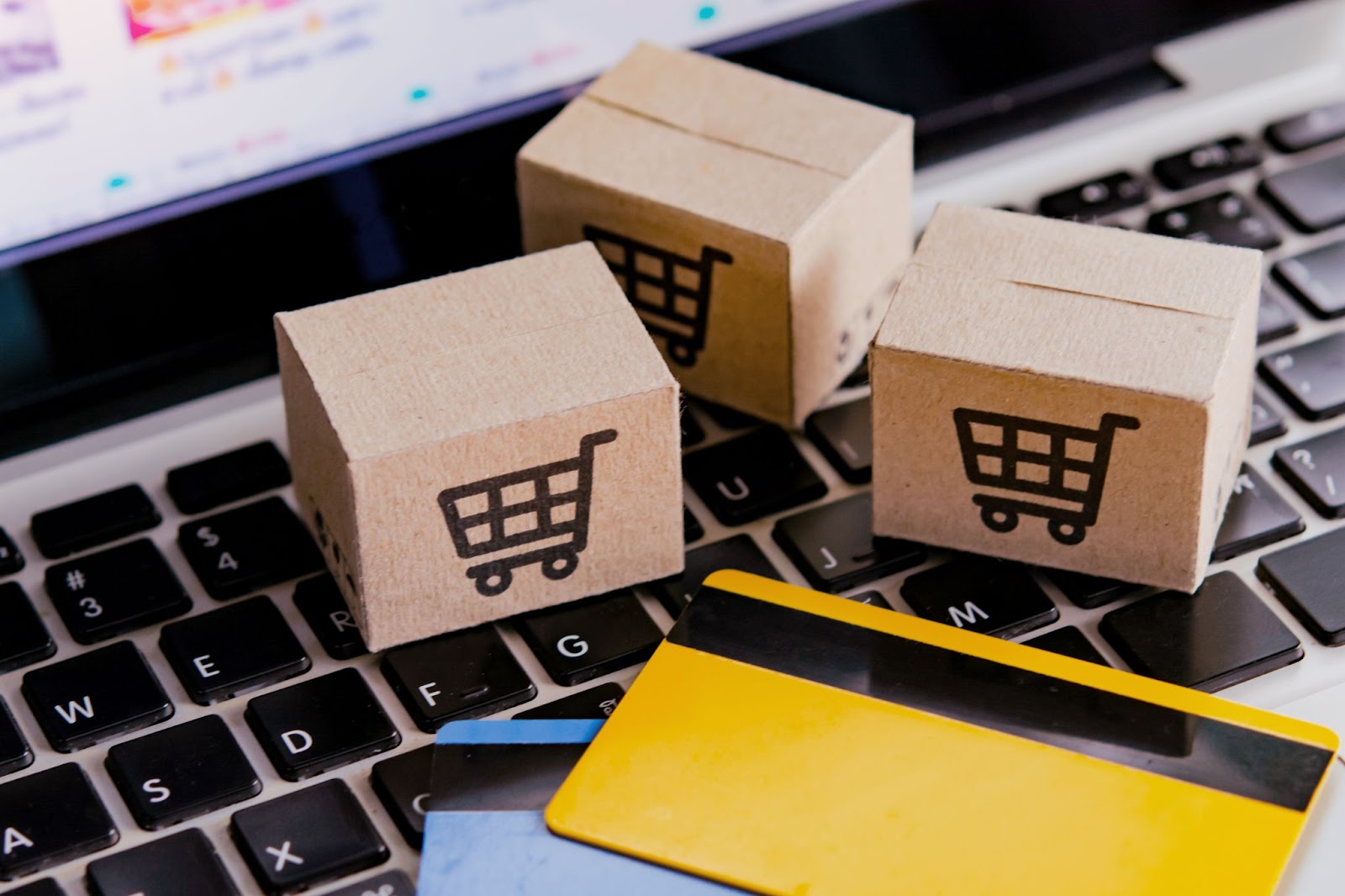 Boxes with shopping cart logos next to credit cards and a computer keyboard.